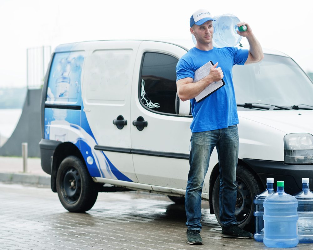 Delivery man with clipboard in front cargo van delivering bottles of water.